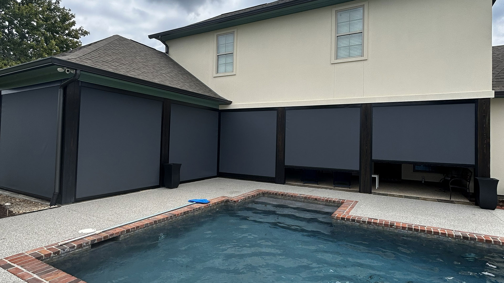 Motion screens enclosing a poolside patio to provide shade, privacy, and comfort in Lafayette, LA