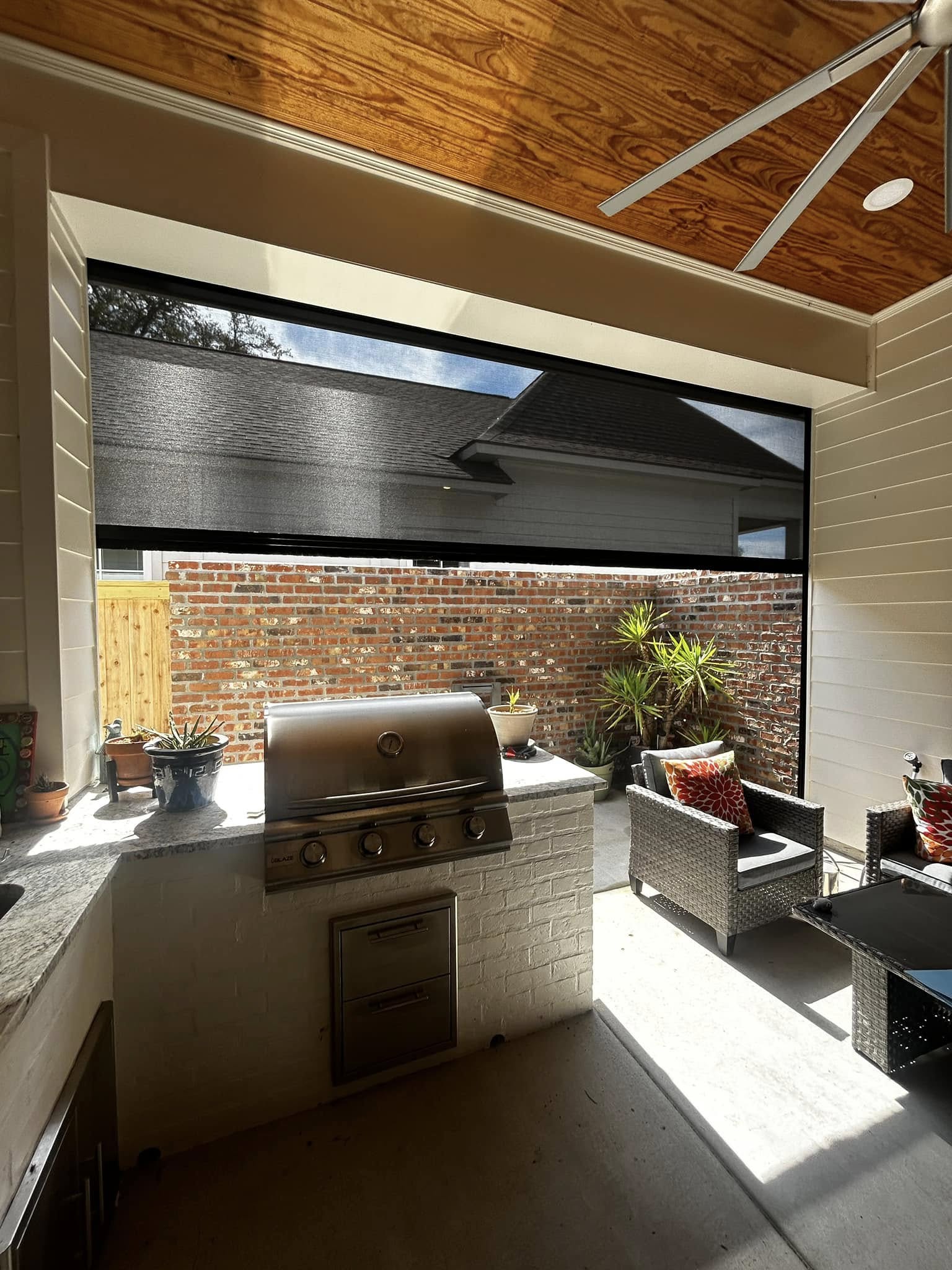 Motorized motion screens enclosing an outdoor kitchen for comfort and protection in Lafayette, Louisiana