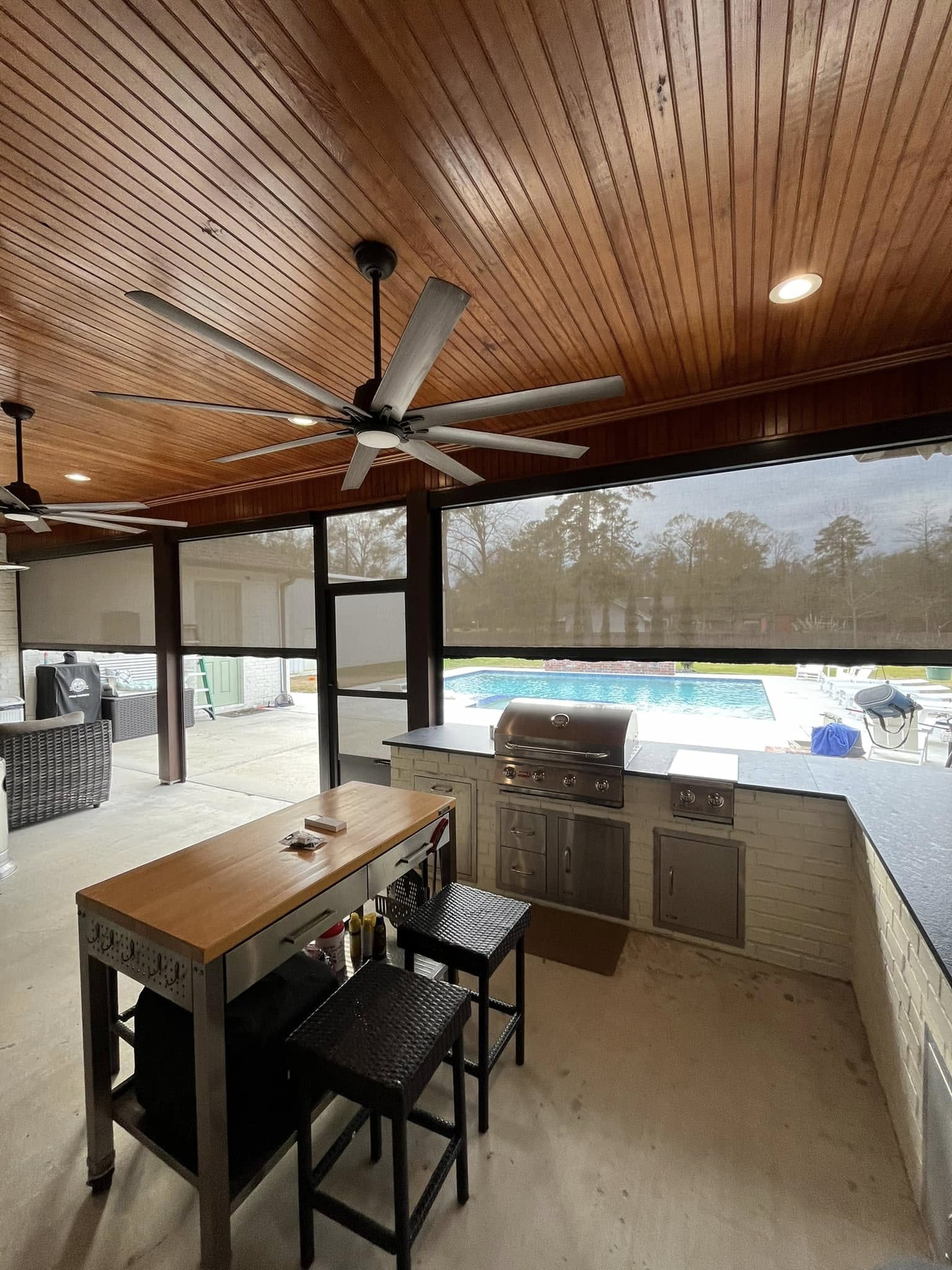 Motion screens enclosing an outdoor kitchen area for shade and ventilation in Lafayette, Louisiana